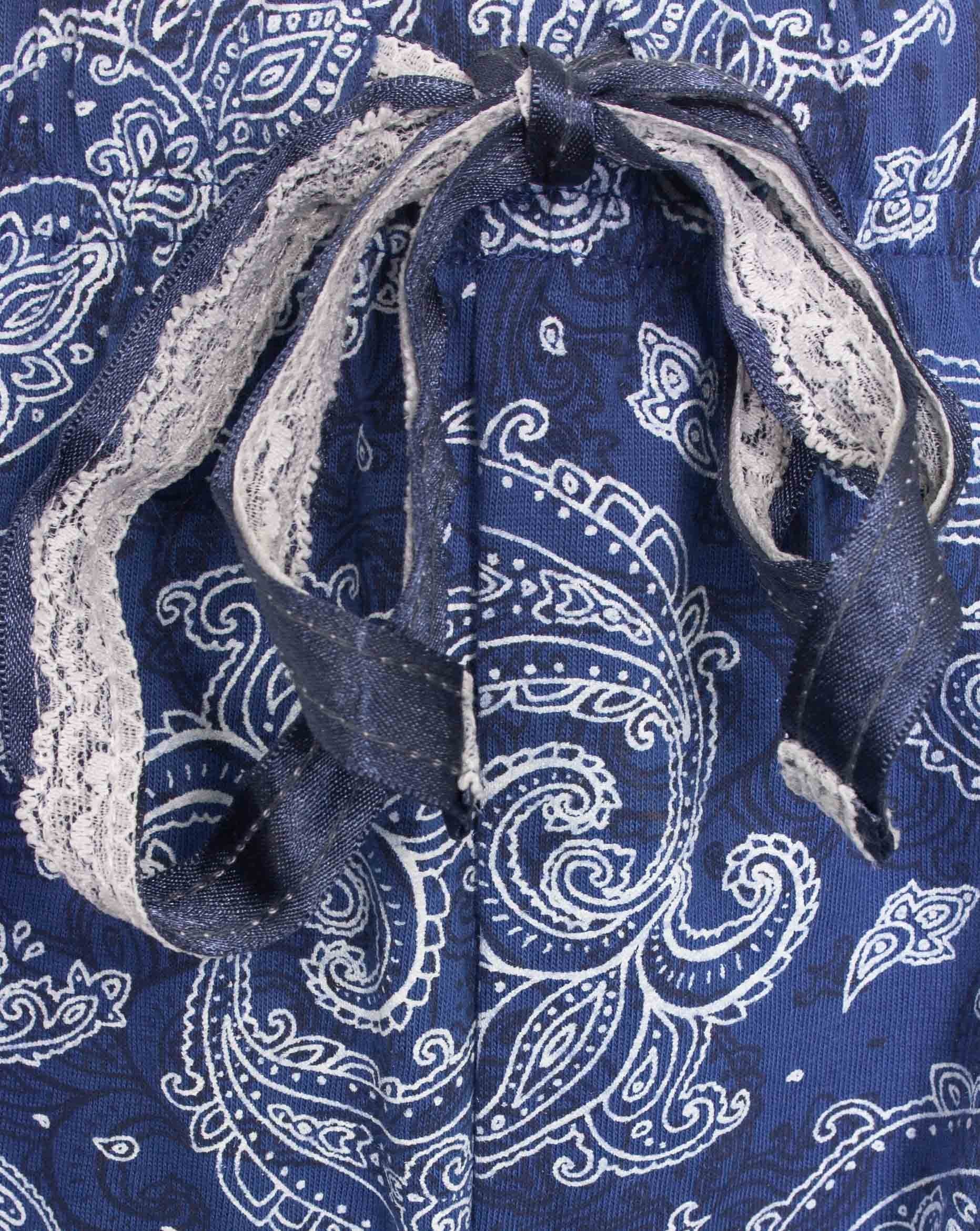Close-up van blauwe katoenen pyjama met wit paisleypatroon en kanten detail aan de hals