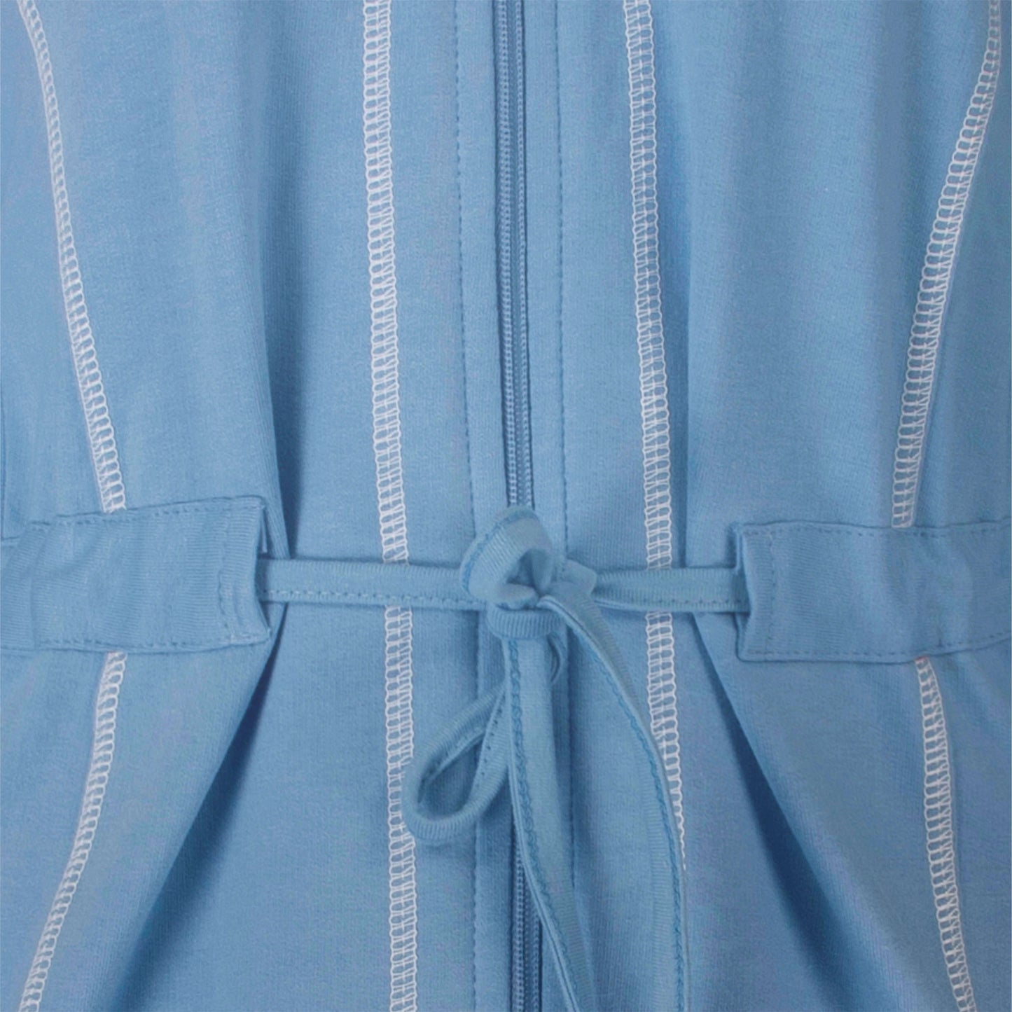 Lichtblauwe huispak met witte stiksels, rits en taillekoord. Close-up van de stof en details.