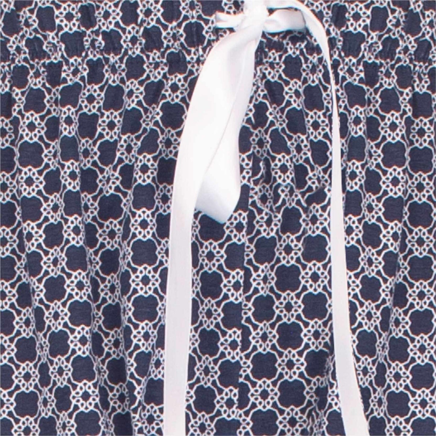 Close-up van navy blauwe katoenen pyjamastof met wit medaillon patroon en wit lint