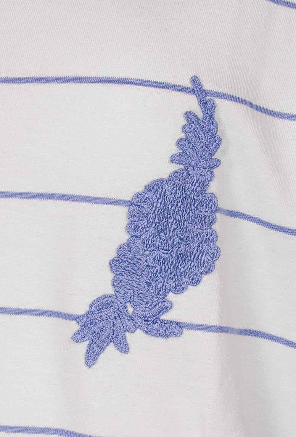 Wit katoenen stof met lichtblauwe strepen en een geborduurde bloem in lichtblauw garen.