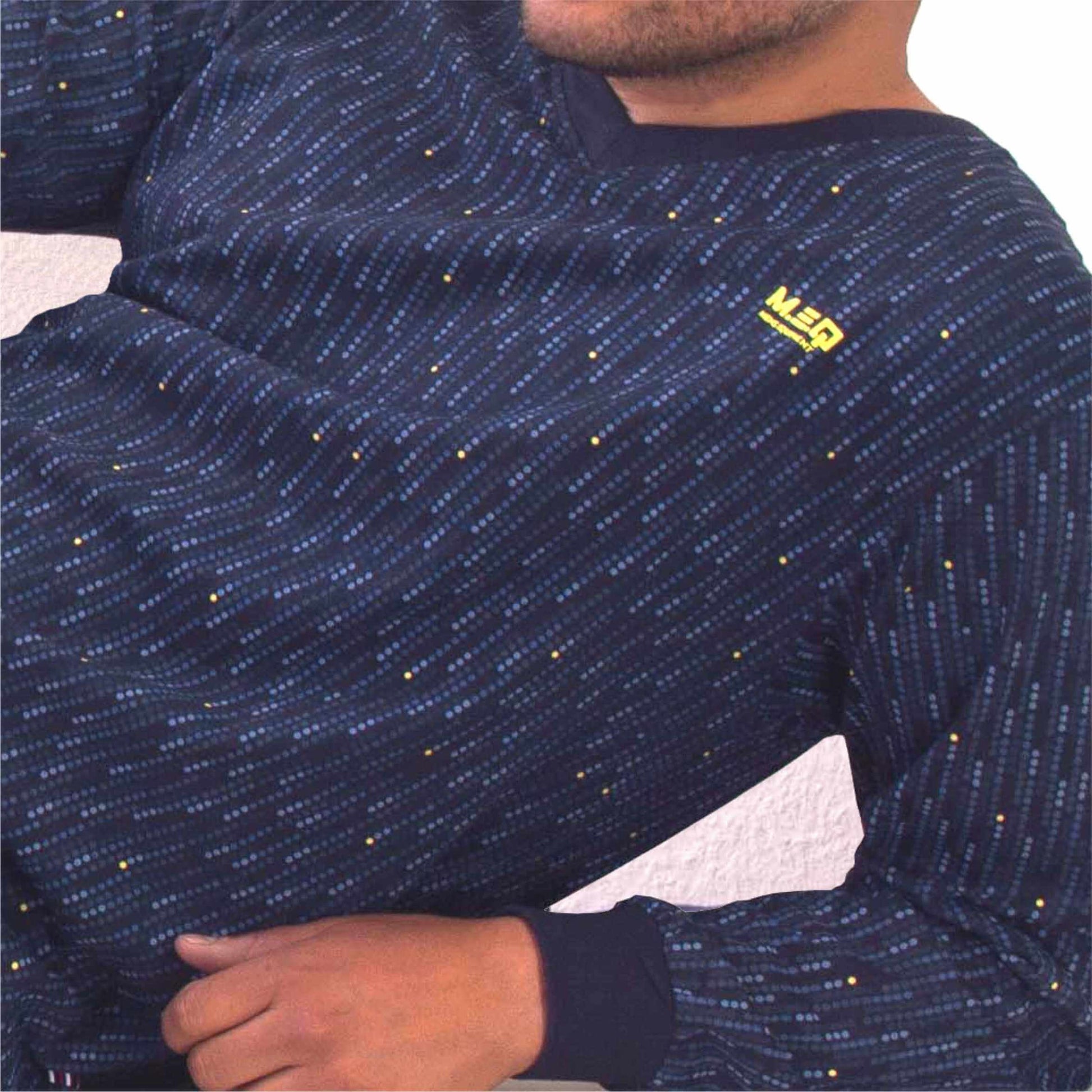 Blauwe pyjama top met lange mouwen, V-hals en gespikkeld patroon. MEQ-logo zichtbaar op de borst.