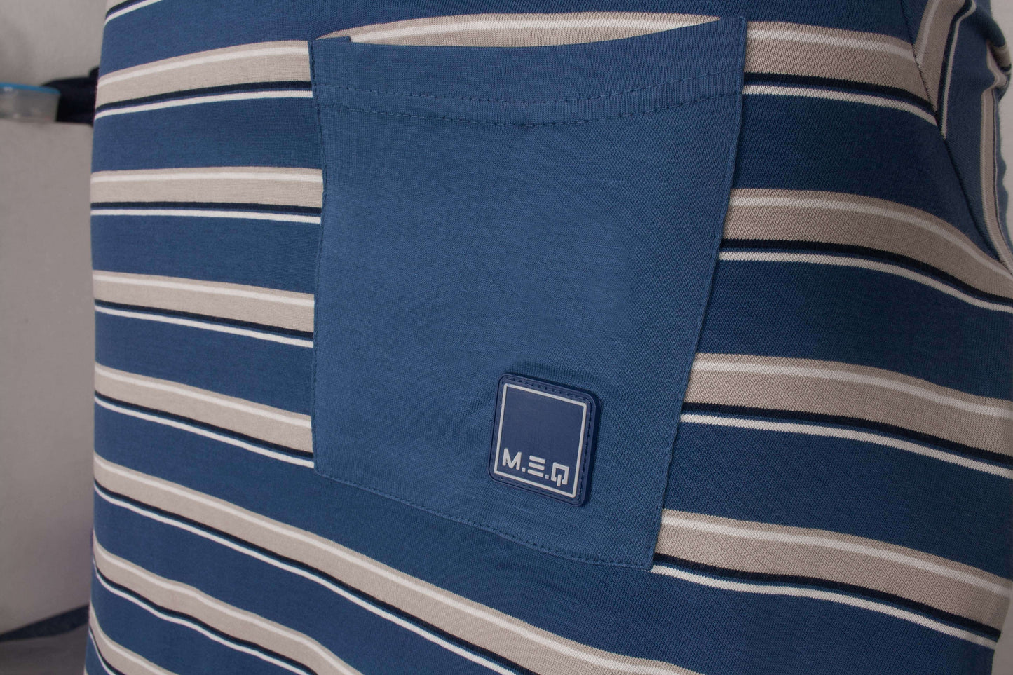 Blauwe pyjama met witte strepen, dichte weergave van de stof en MEQ-logo op de borstzak