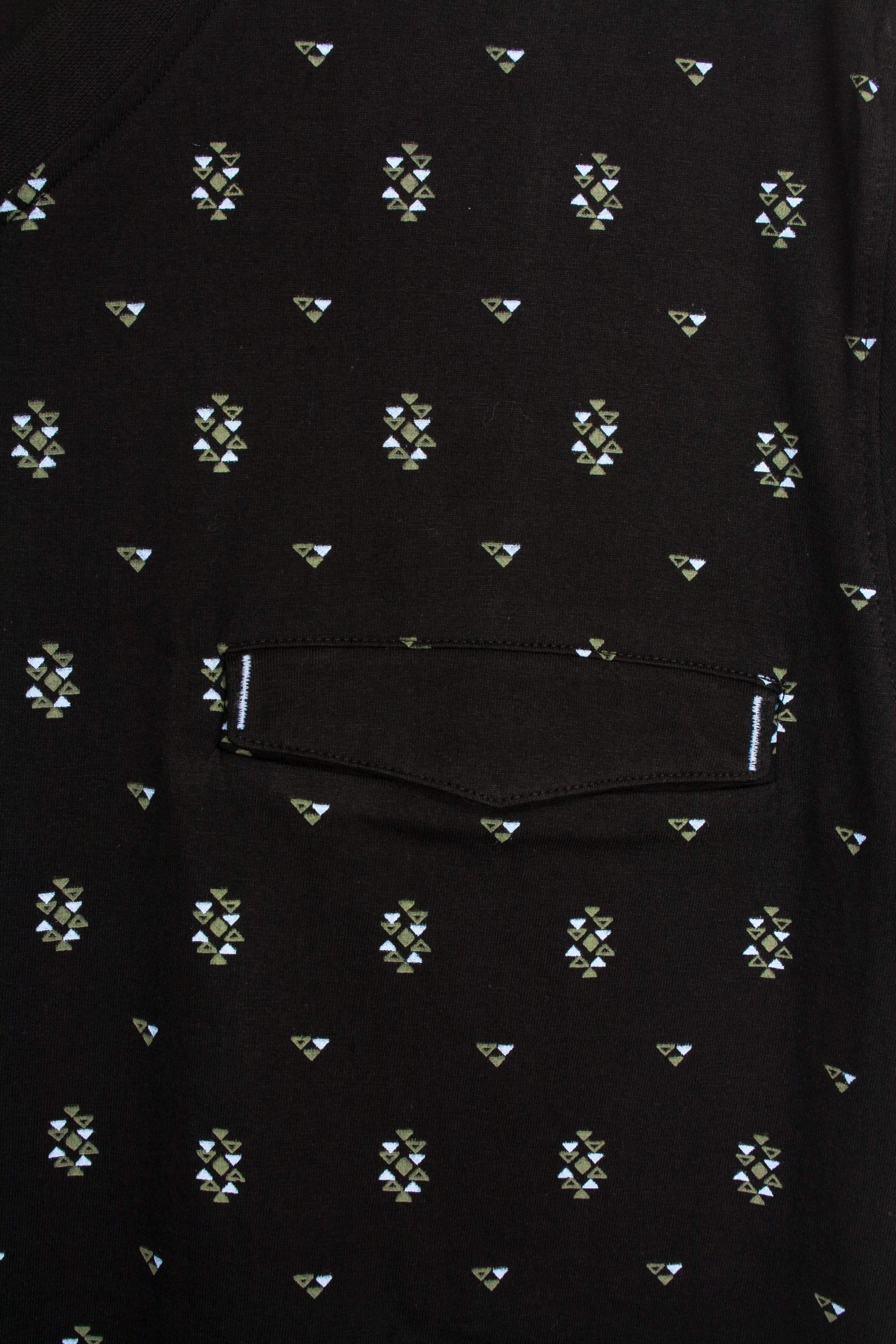 Zwarte stof met geometrisch patroon van kleine driehoeken in wit en groen. Zichtbare zak met stiksels.