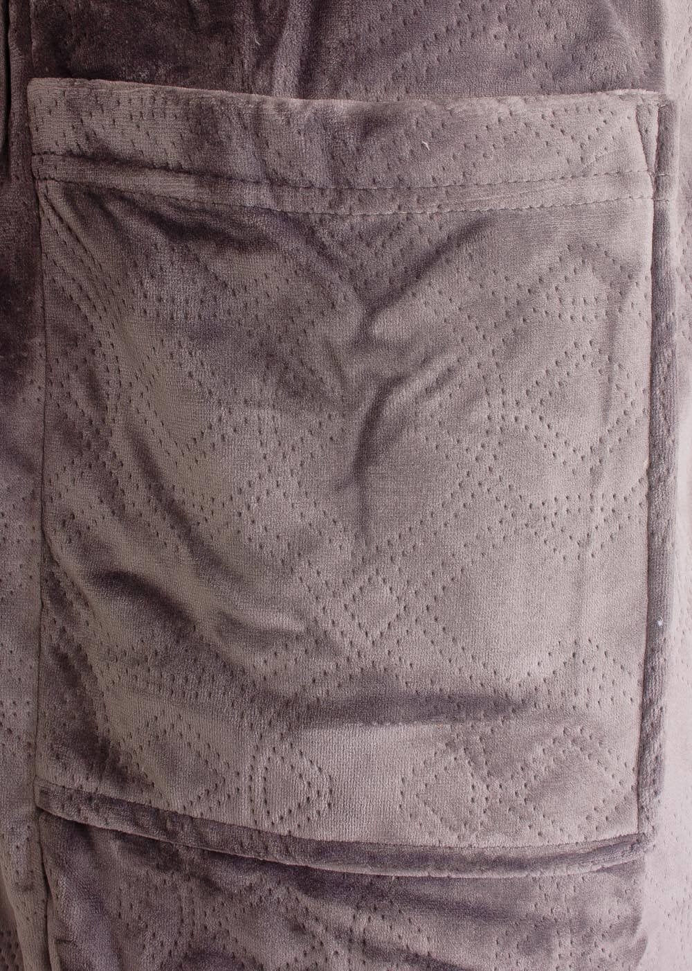 Close-up van een beige fleece badjas met gestanst dessin en opgestikte zak, gemaakt van zacht velours materiaal.