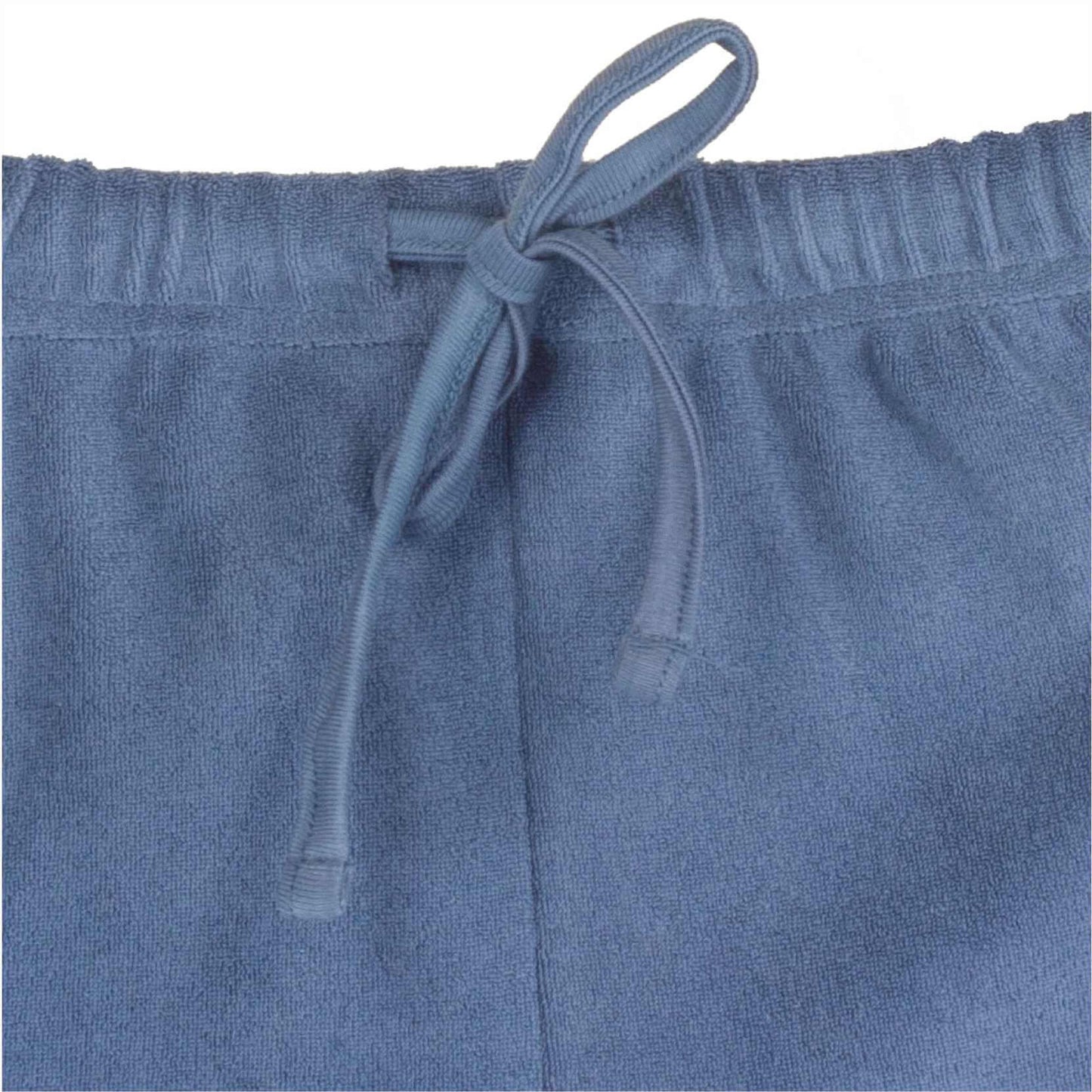 Close-up van een blauwe badstof pyjama broek met een elastische tailleband en een aantrekkoord.