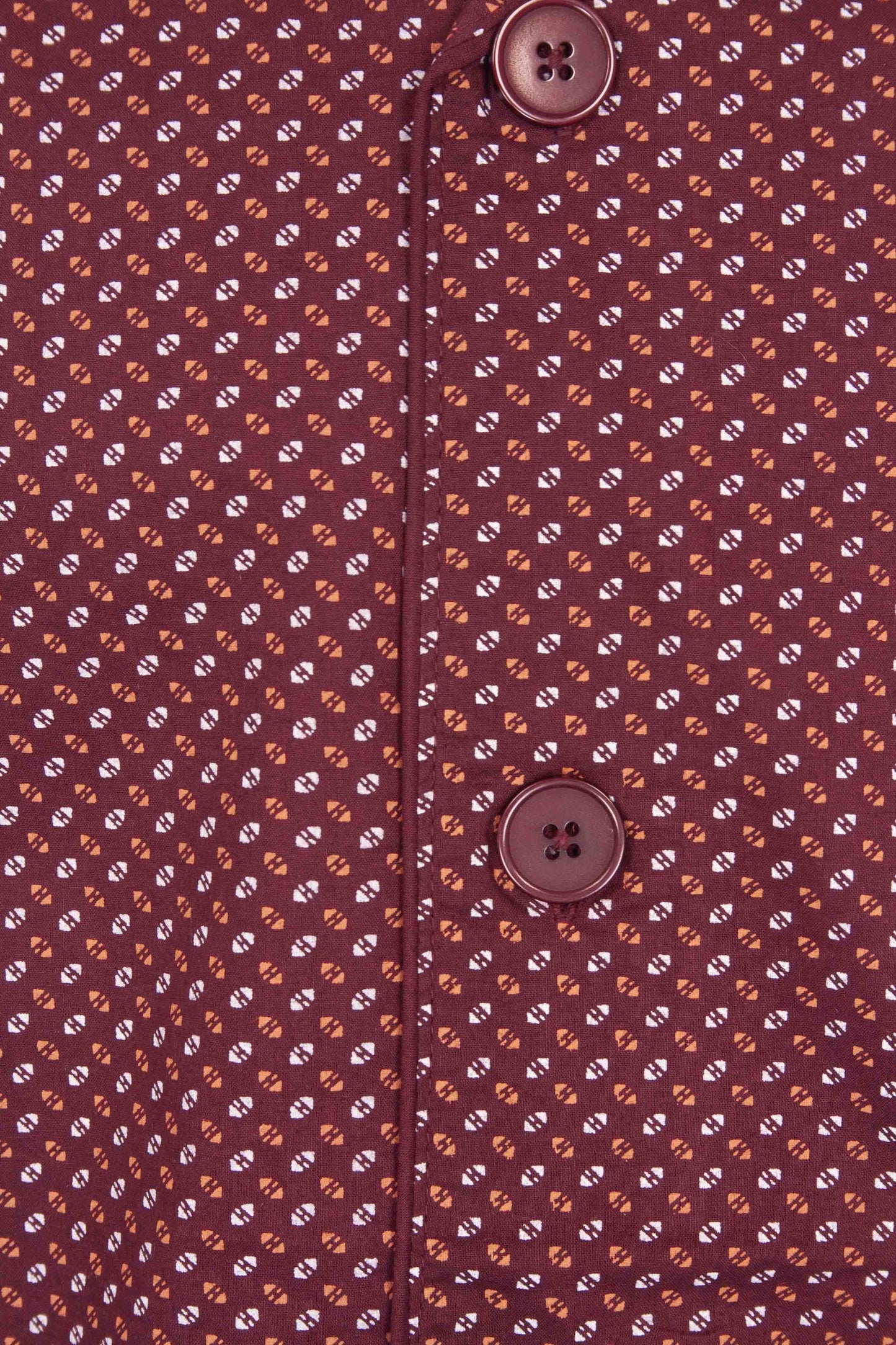 Rode doorknoop pyjama met wit en oranje geometrisch patroon. Twee knoppen zichtbaar op de voorkant.