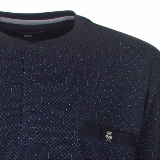 Close-up van een donkerblauwe pyjama met subtiel geprint dessin, polosluiting en een klein logo op de borstzak.