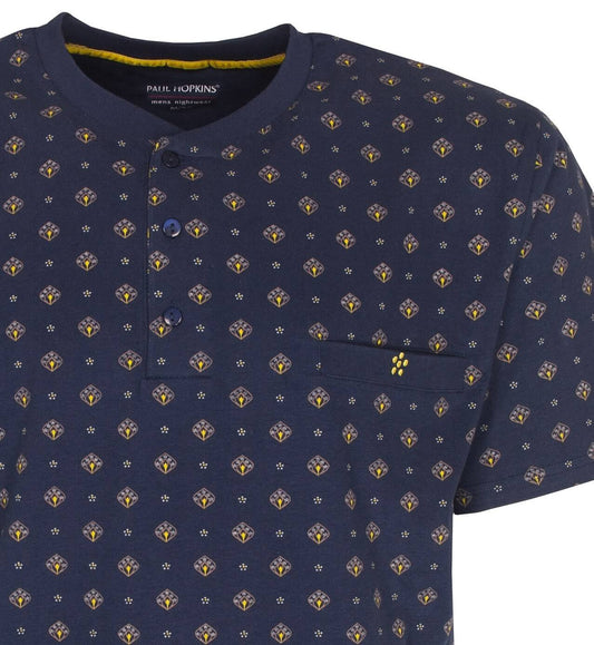 Donkerblauwe pyjama top met korte mouwen, bedrukt met kleine gele en witte motieven, knopen aan de hals