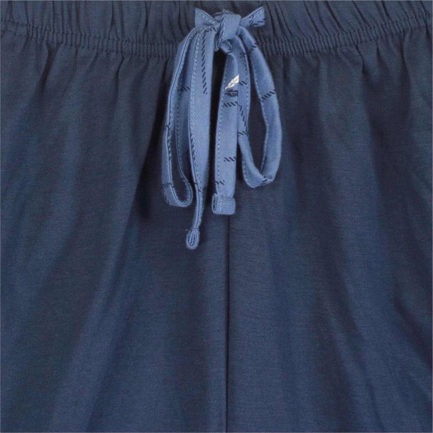 Close-up van lichtblauwe pyjama stof met elastische band en wit koord met gestreept patroon.