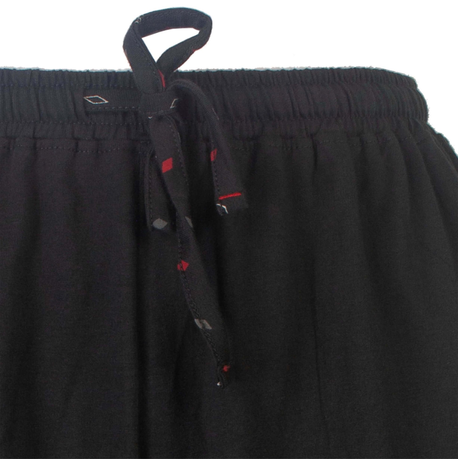 Close-up van de elastische taille vanleband van een zwarte pyjamabroek met rode accenten en een trekkoord.