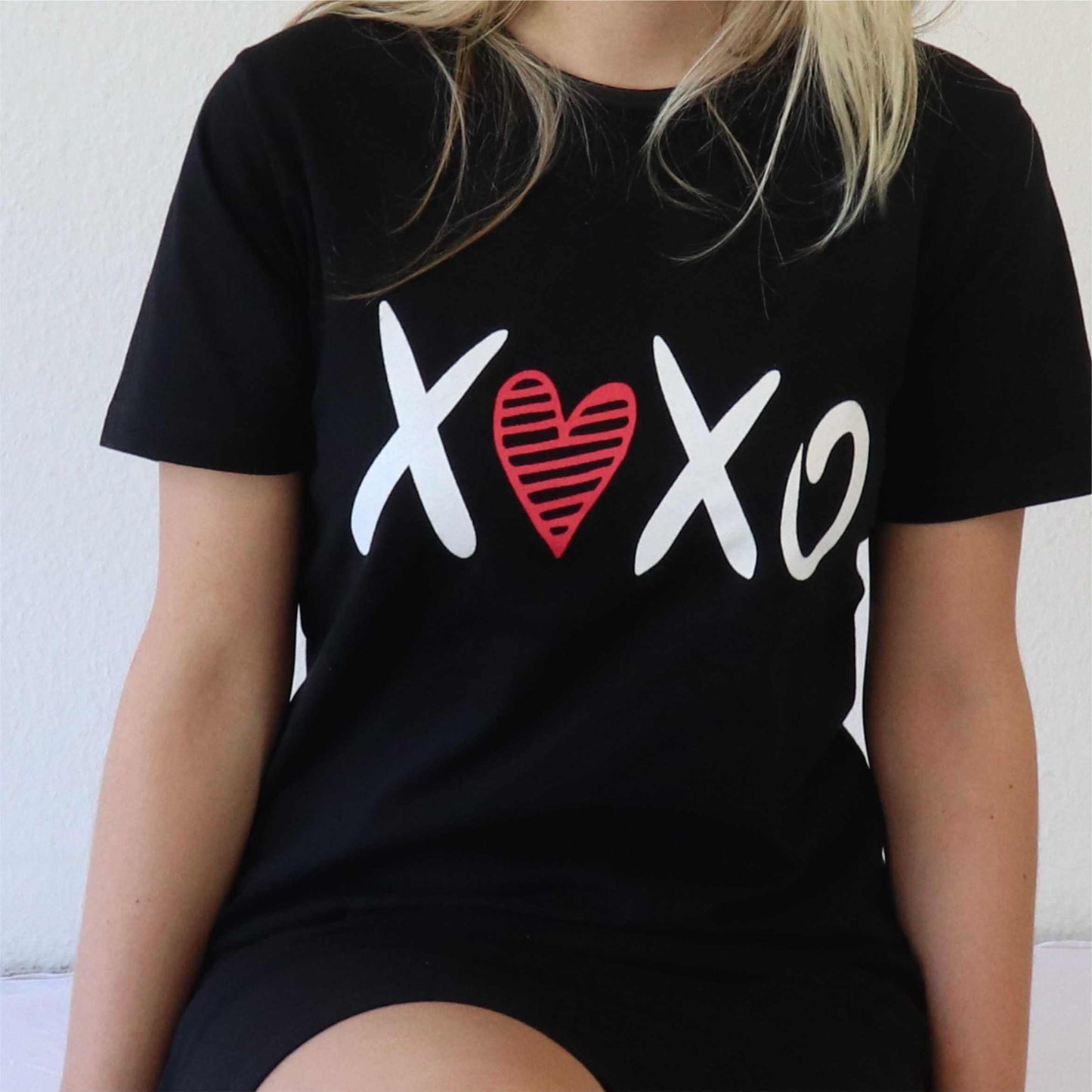 Zwart nachthemd met korte mouwen en witte 'XOXO' print, waarbij het hart rood is. Gedragen door blonde vrouw.