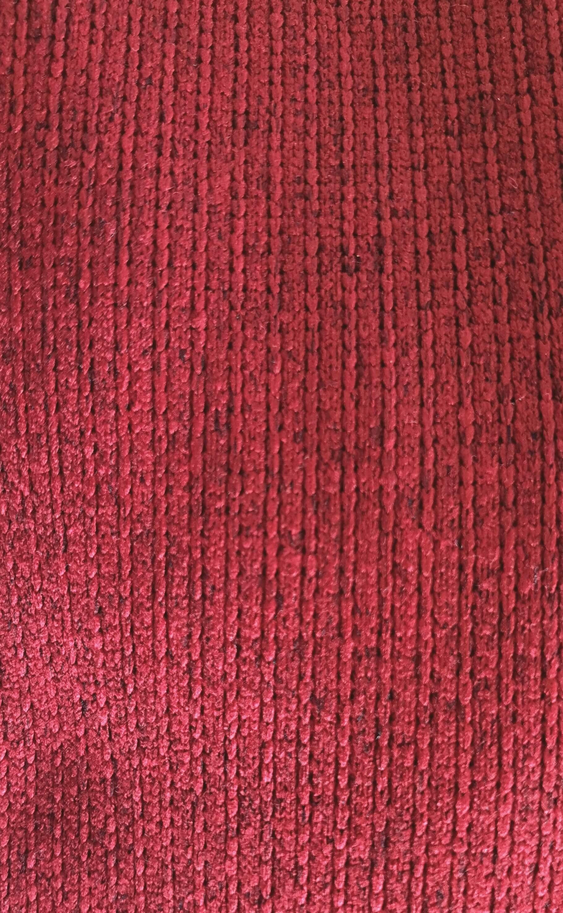 Close-up van rood gebreide stof met een jacquardpatroon, zacht en comfortabel ogend materiaal voor een kamerjas.