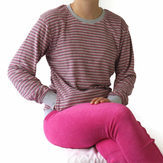 Gestreepte badstof pyjama top in grijs en roze, met roze broek. Close-up van de torso en bovenbenen.