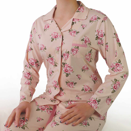 Roze dames pyjama met lange mouwen en doorknoop sluiting, versierd met roze rozenprint over het hele kledingstuk.