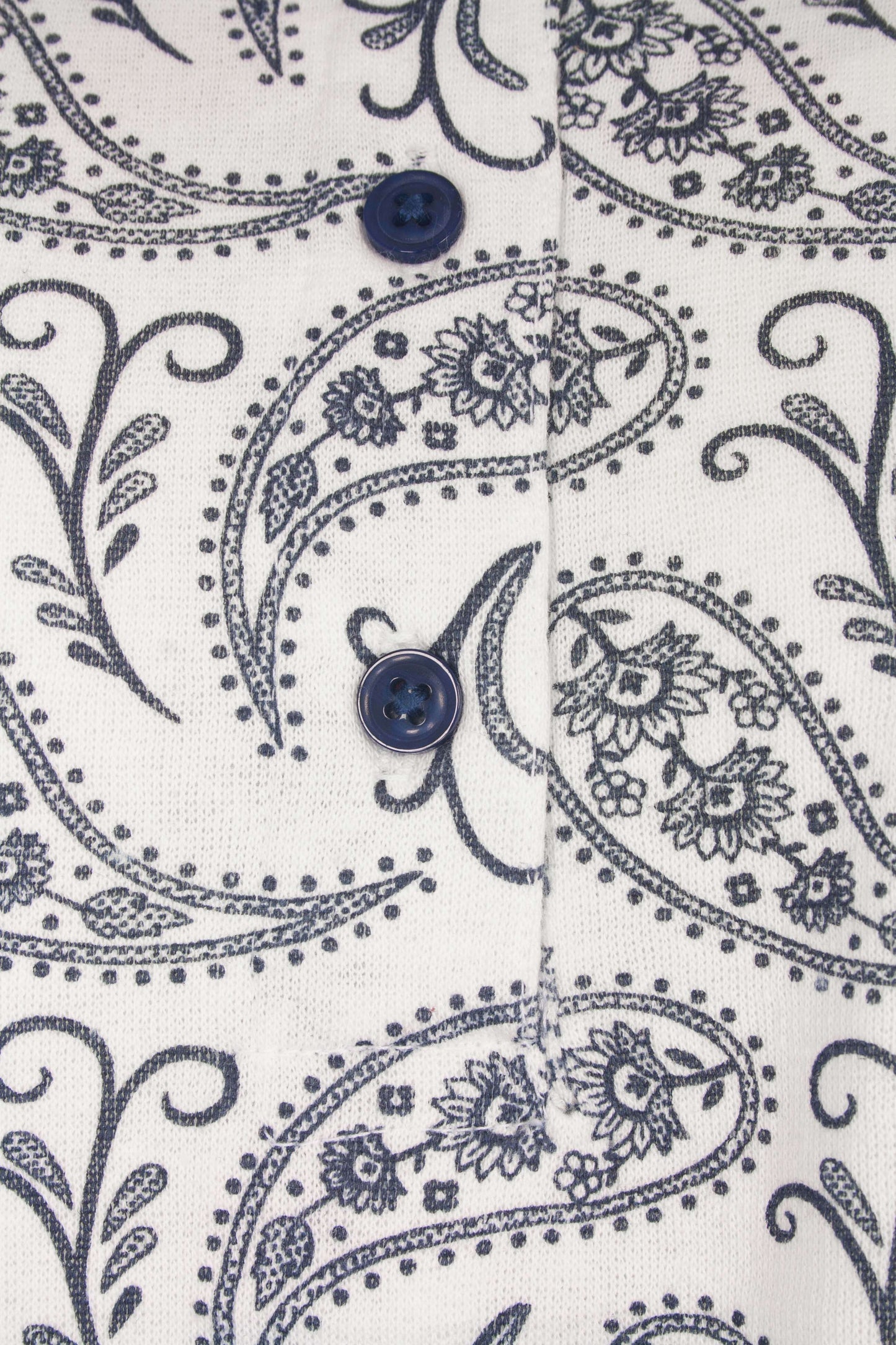 Dames pyjama met blauw paisley patroon op witte achtergrond, twee blauwe knopen zichtbaar, fleece materiaal