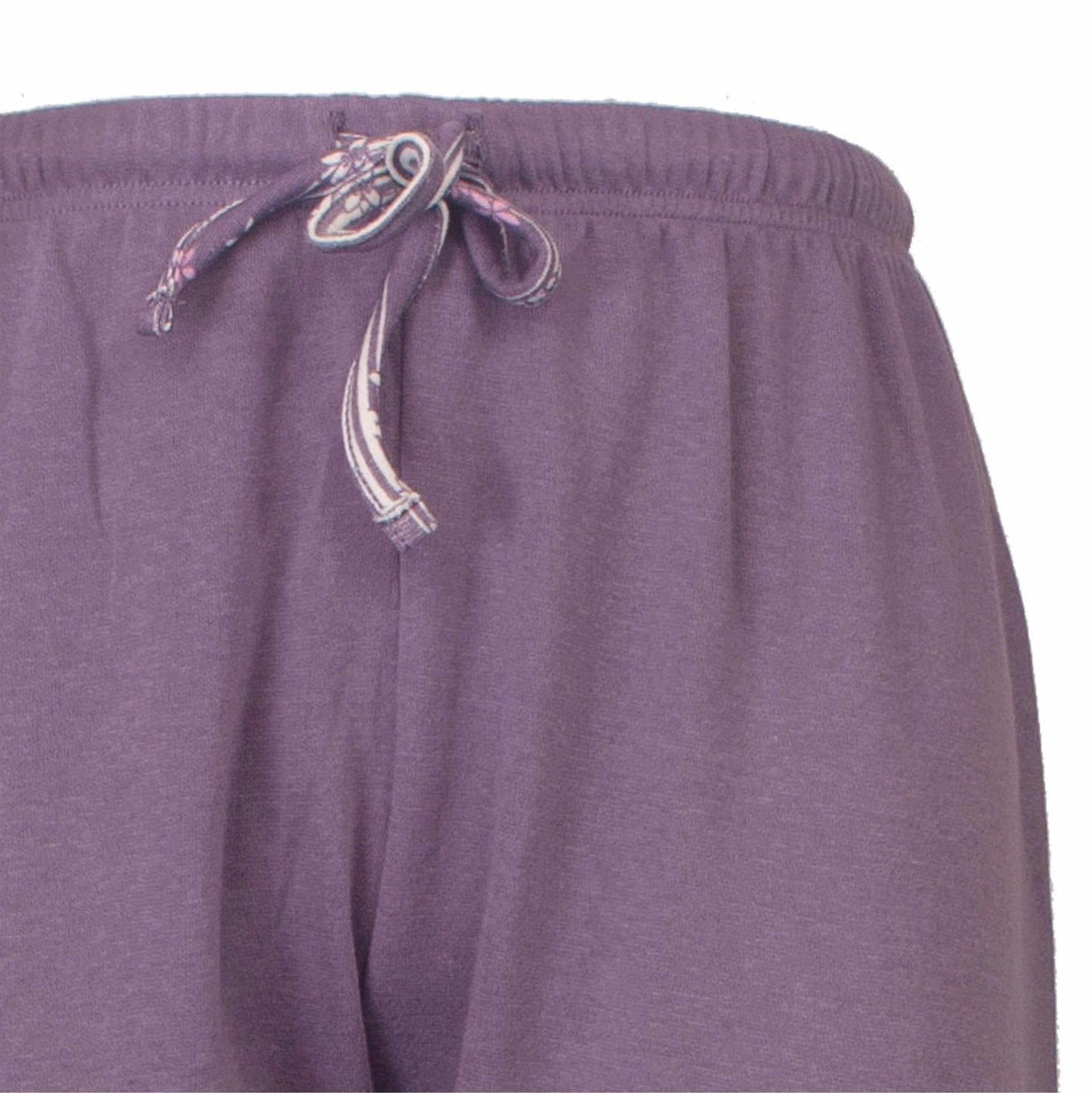 Close-up van een paarse fleece pyjamabroek met een gebloemde trekkoord in de tailleband.