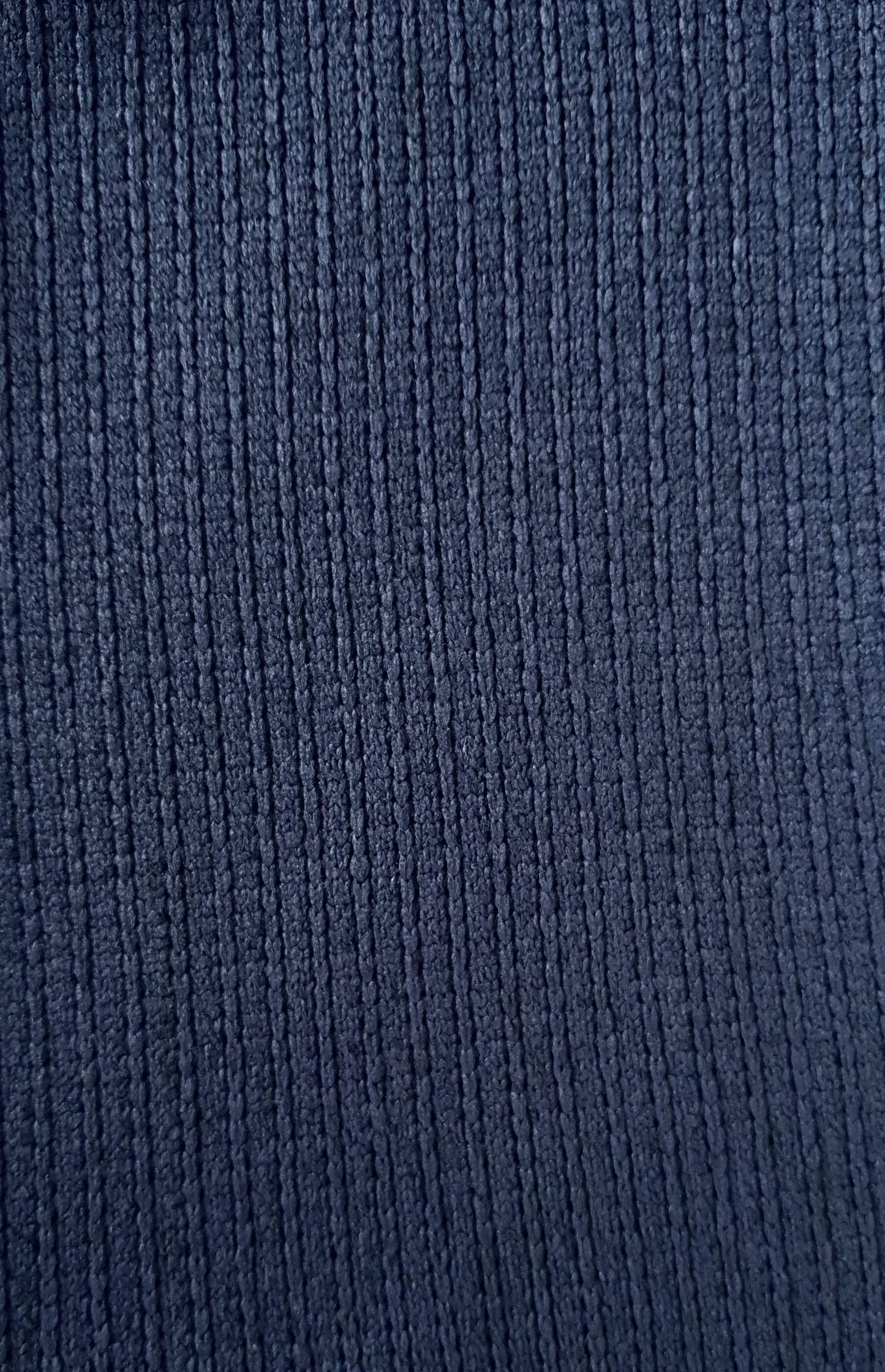 Close-up van donkerblauwe fleece stof met verticale ribbelstructuur, zacht en comfortabel ogend.