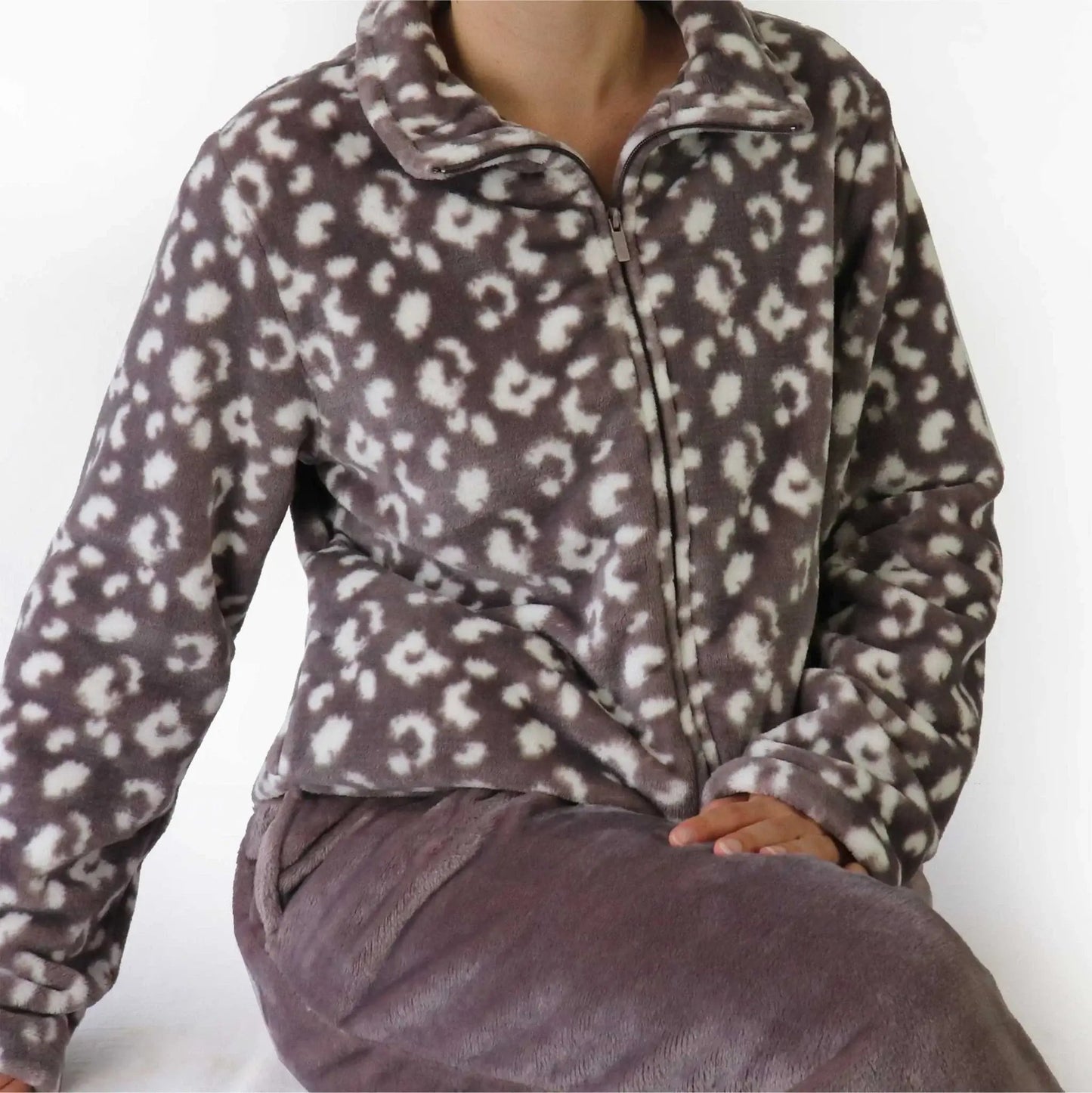 Bruine fleece huispak met witte panterprint, ritssluiting en opstaande kraag, gecombineerd met een bruine broek.