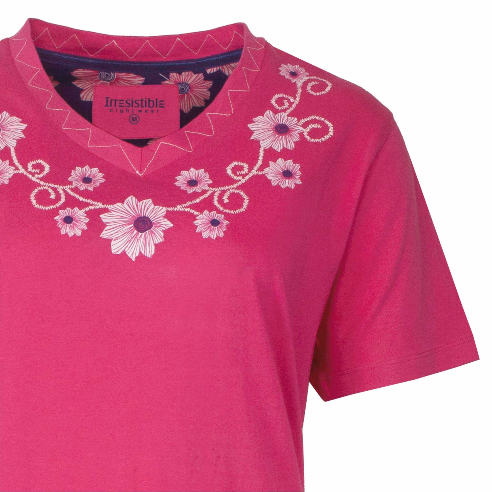 Roze nachthemd met V-hals en korte mouwen, versierd met witte bloemen en krullen borduurwerk rond de hals