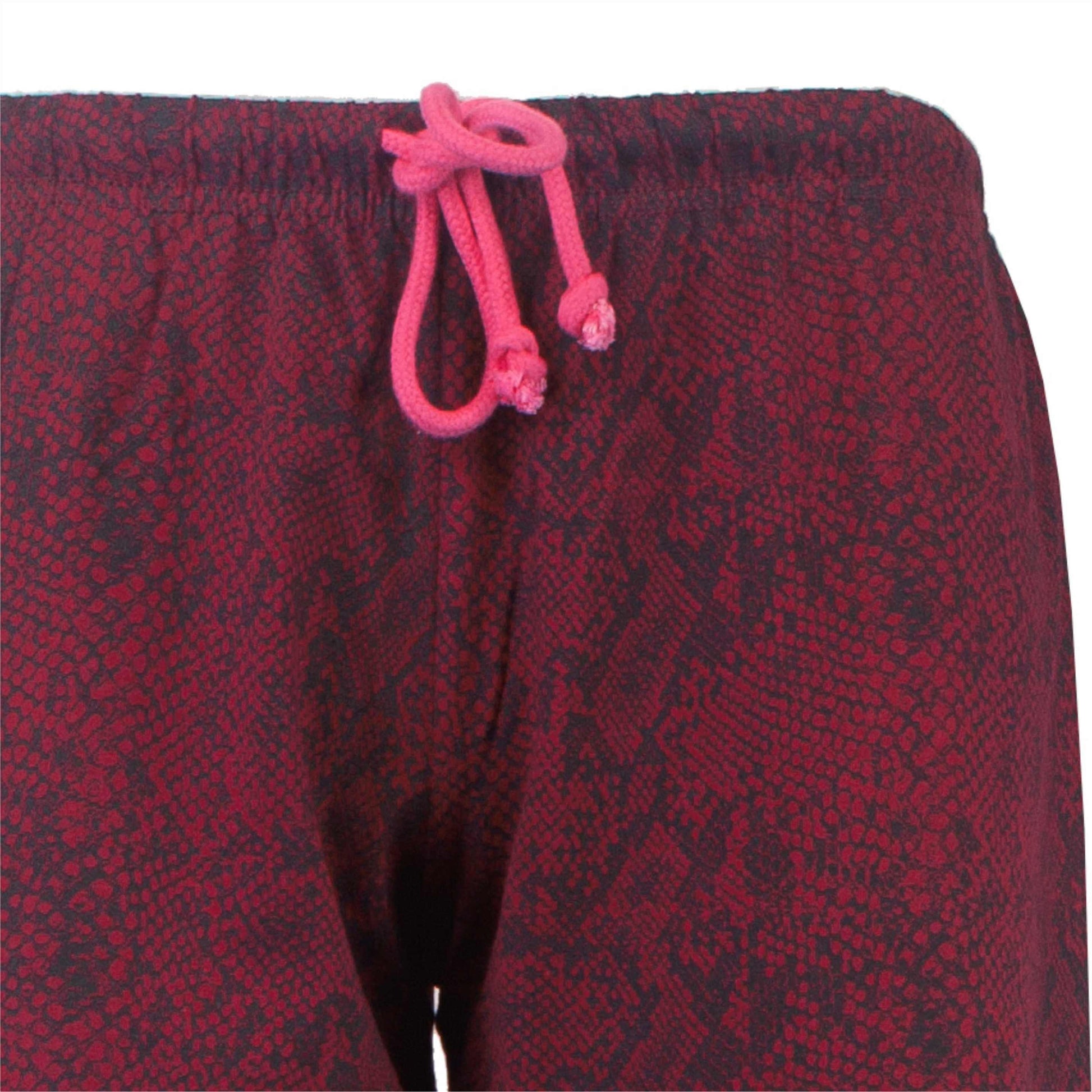 Close-up van bordeauxrode pyjama-broek met roze trekkoord. Gedetailleerd patroon zichtbaar op de stof.