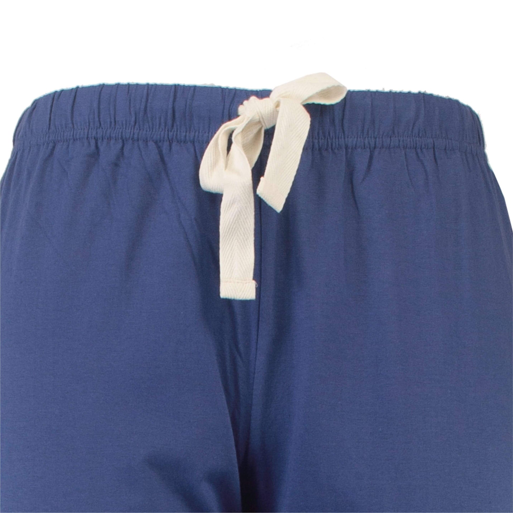 Close-up van een donkerblauwe pyjamabroek met een elastische tailleband en een wit trekkoord.