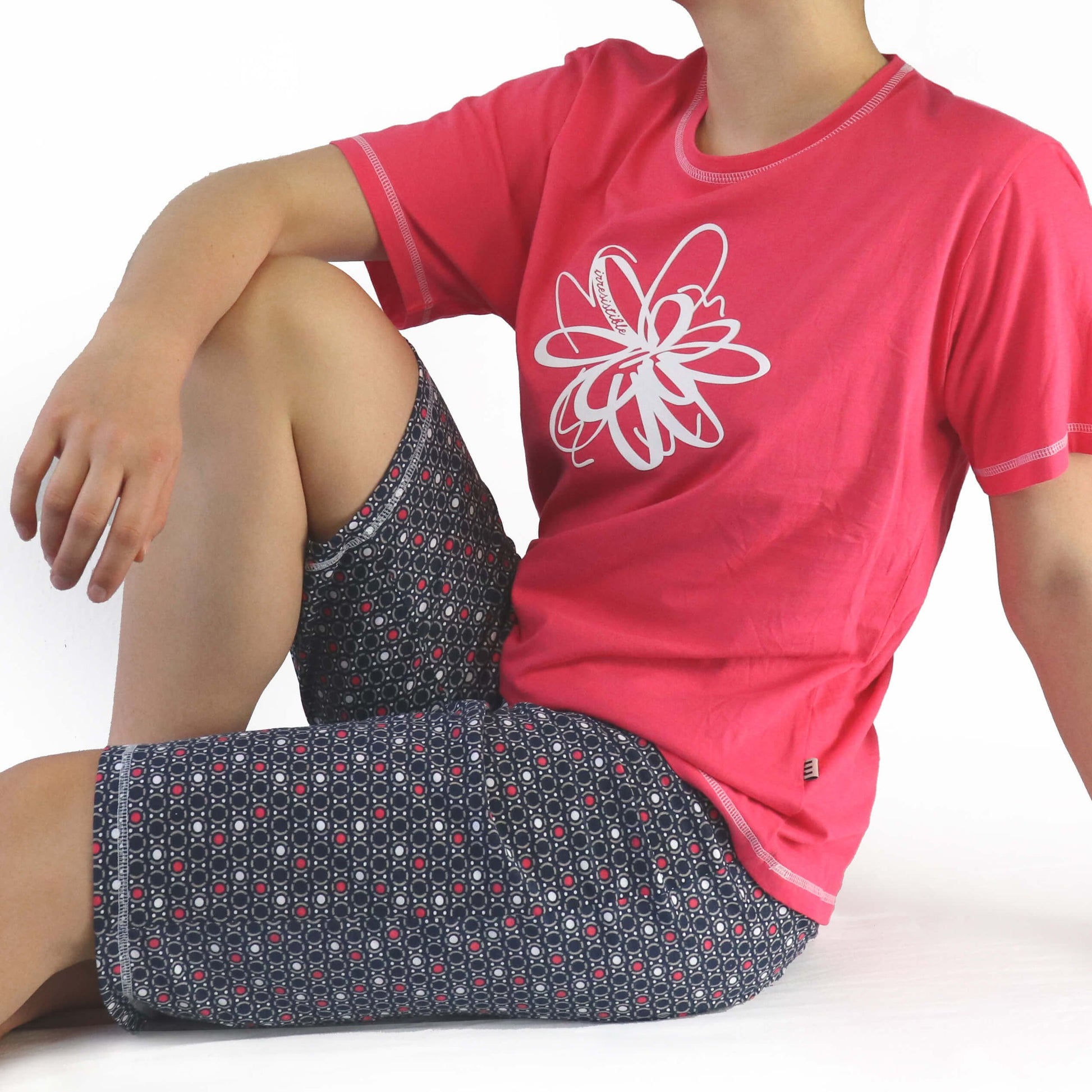 Rode dames pyjama met witte bloem, korte mouwen en bijpassende broek met geometrisch patroon in grijs en rood.