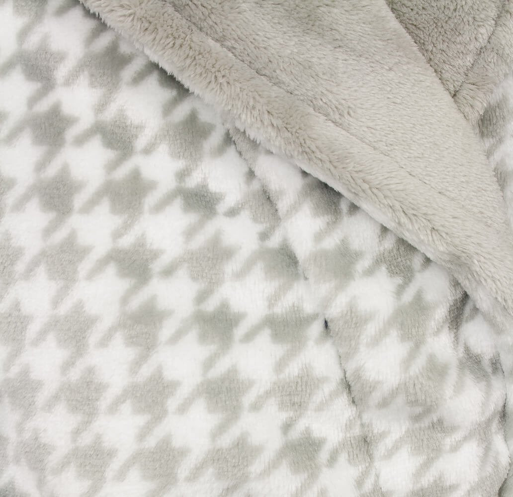 Close-up van zachte grijze fleece stof met pied-de-poule patroon, gedeeltelijk bedekt door effen fleece.