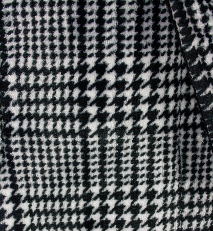 Close-up van zwart-wit geruite stof met houndstooth patroon, typisch voor een fleece badjas.