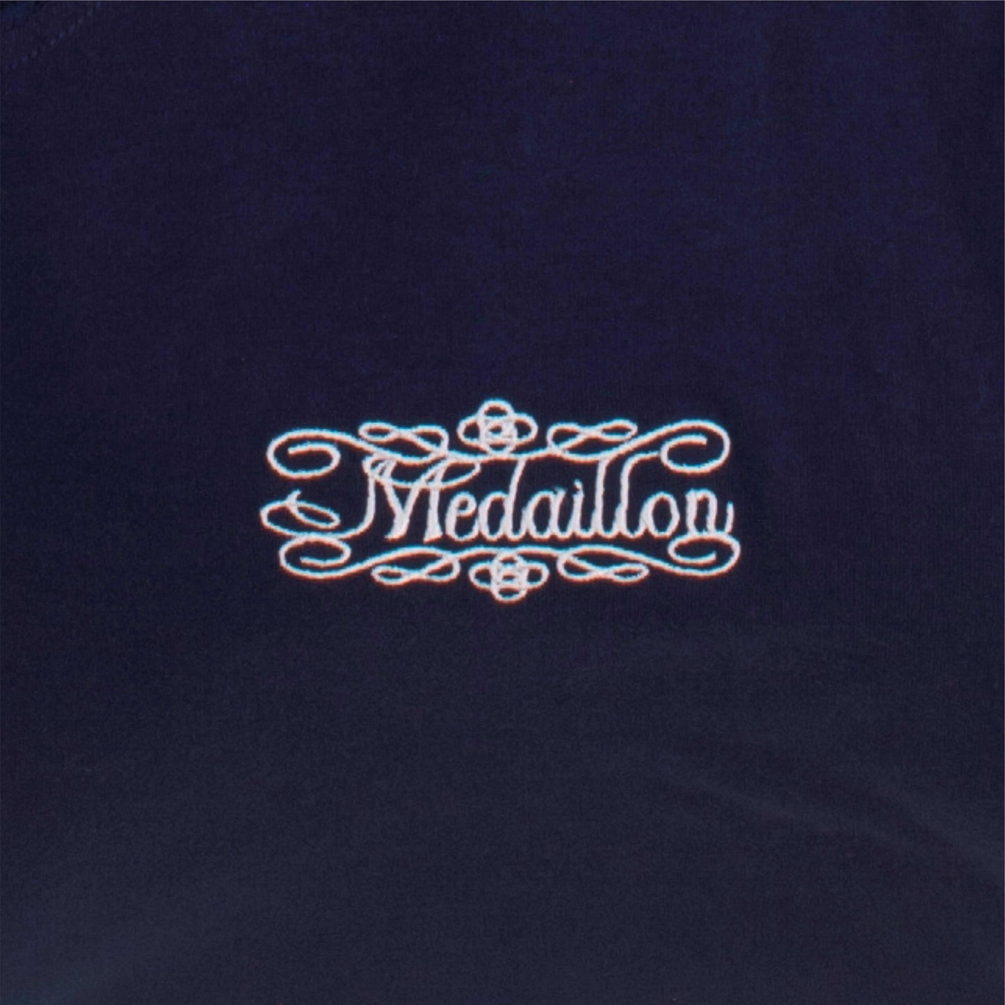 Elegant logo 'Medaillon' in sierlijke letters op donkerblauwe achtergrond, omringd door decoratieve krullen.