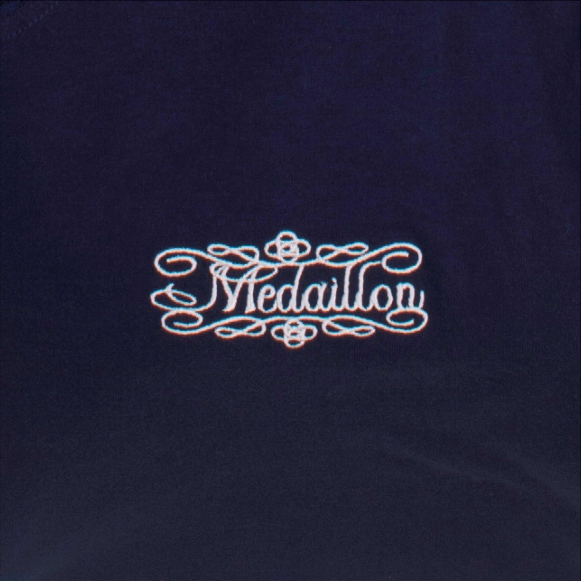 Elegant logo 'Medaillon' in sierlijke letters op donkerblauwe achtergrond, omringd door decoratieve krullen.