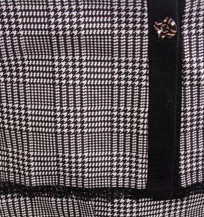 Zwart-wit ruitpatroon nachthemd met zwarte rand en goudkleurige knoop, close-up van stof en sluiting