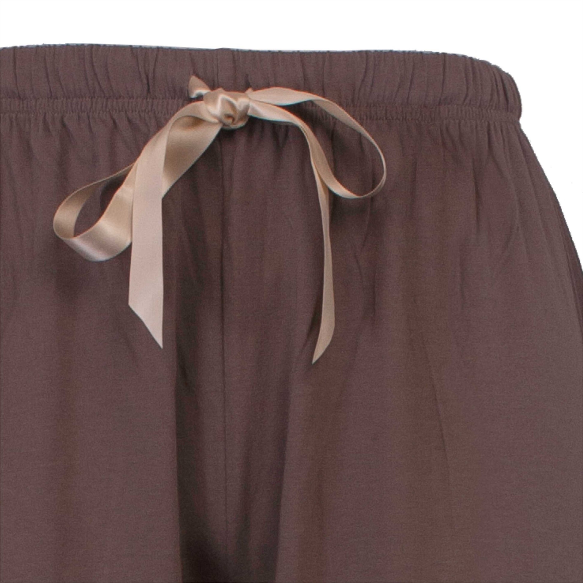 Bruine pyjama broek met een beige satijnen lint als decoratief element aan de taille.