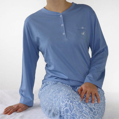 Blauwe dames pyjama met lange mouwen, knoopsluiting en borstzakje. Bijpassende broek met bloemenpatroon.