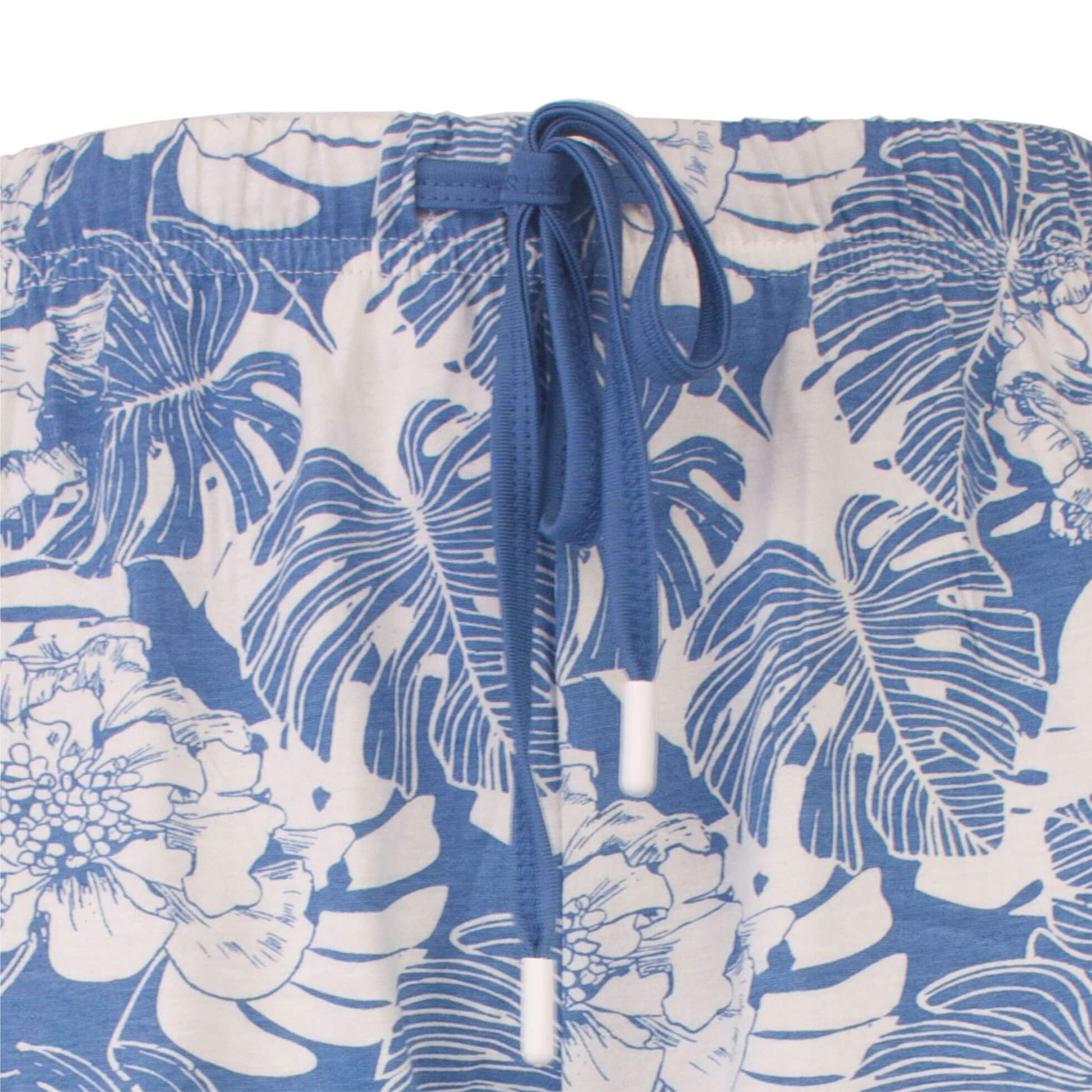 Lichtblauwe pyjama met wit bloemen- en bladpatroon. Elastische taille met blauw koord zichtbaar.