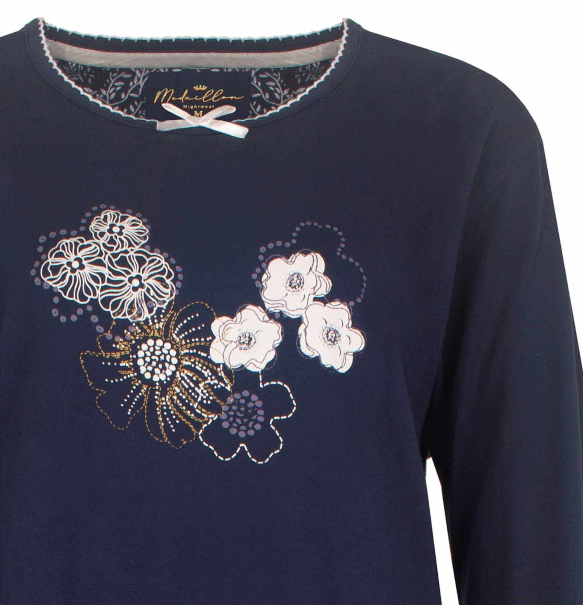 Donkerblauwe dames pyjama met witte en goudkleurige bloemenprint op de voorkant, merk Medaillon zichtbaar.