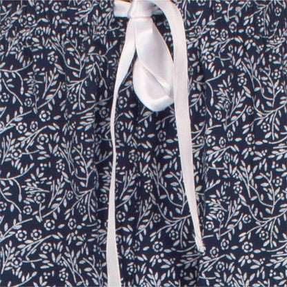 Witte strik op navy blauwe stof met delicaat bloemenpatroon, detail van een dames pyjama