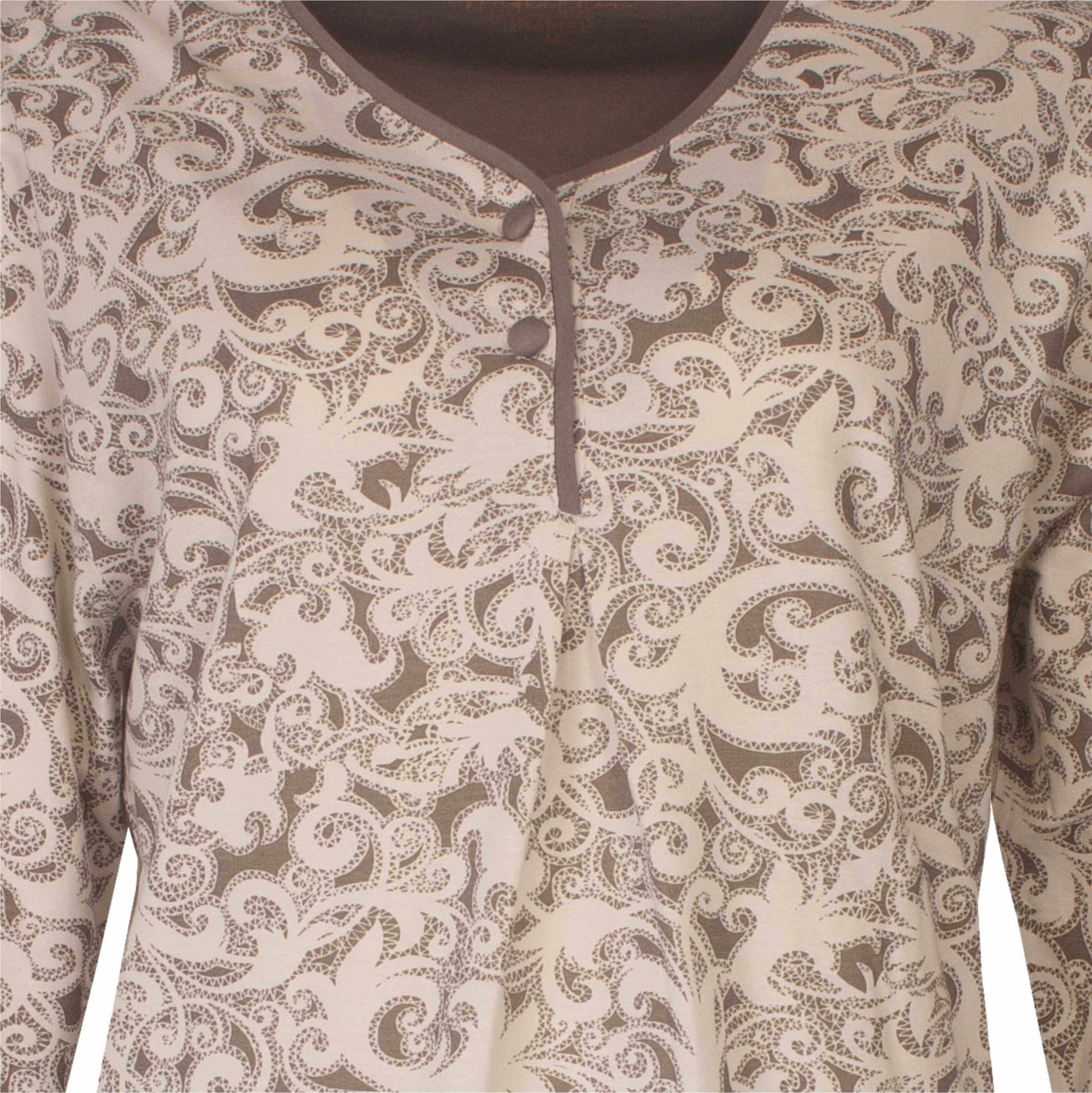 Close-up van een dames pyjama met een sierlijk bruin en crème ornamentpatroon en een gedeeltelijke halsopening met knoopjes.