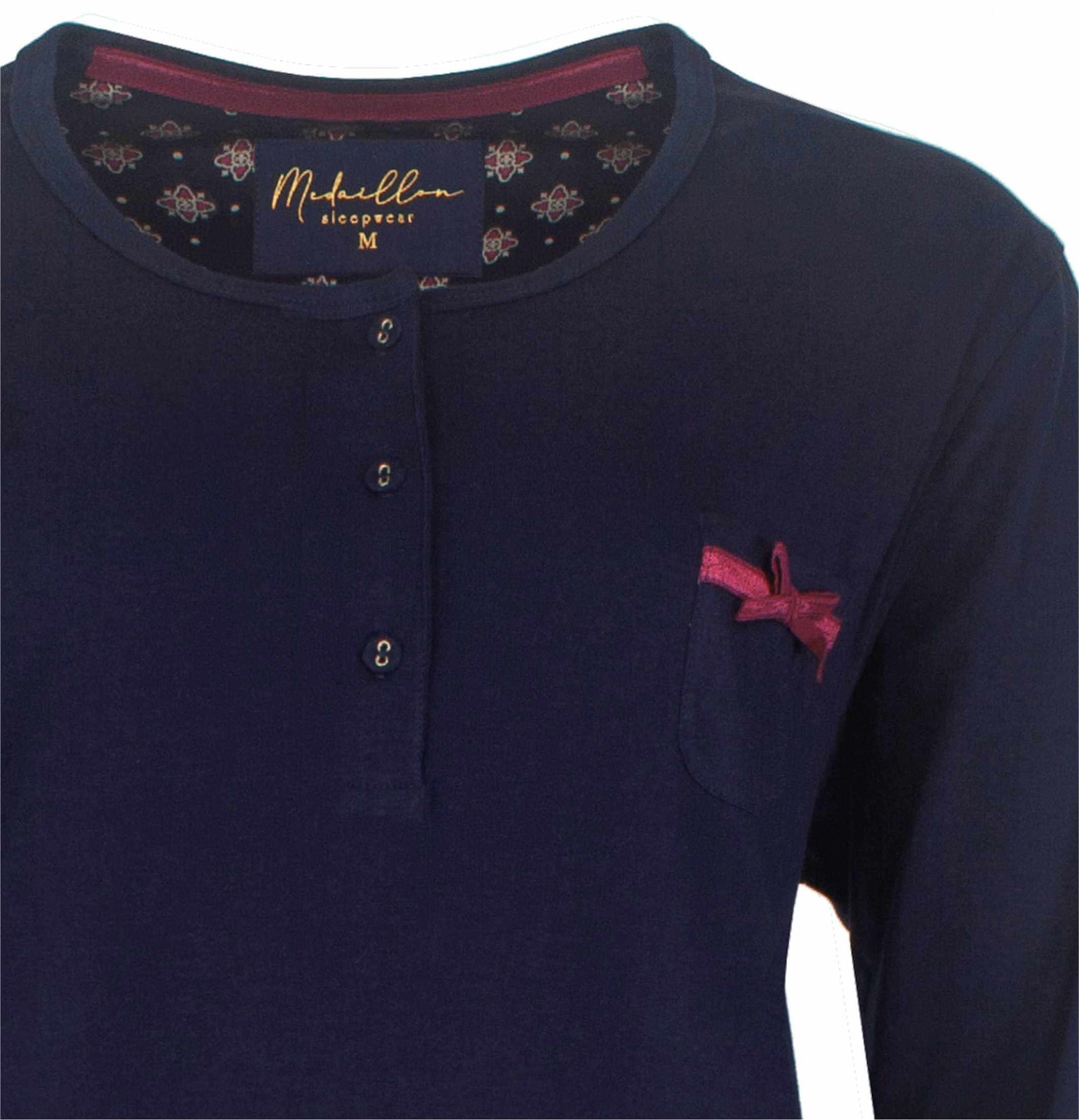 Donkerblauwe dames pyjama met polo sluiting, rood strikje op borstzak en geblomd patroon aan binnenkant kraag