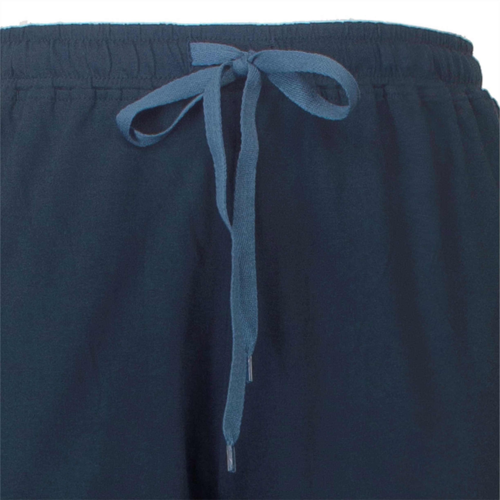 Close-up van een donkerblauwe pyjama broek met een lichtblauw koord als tailleband sluiting.