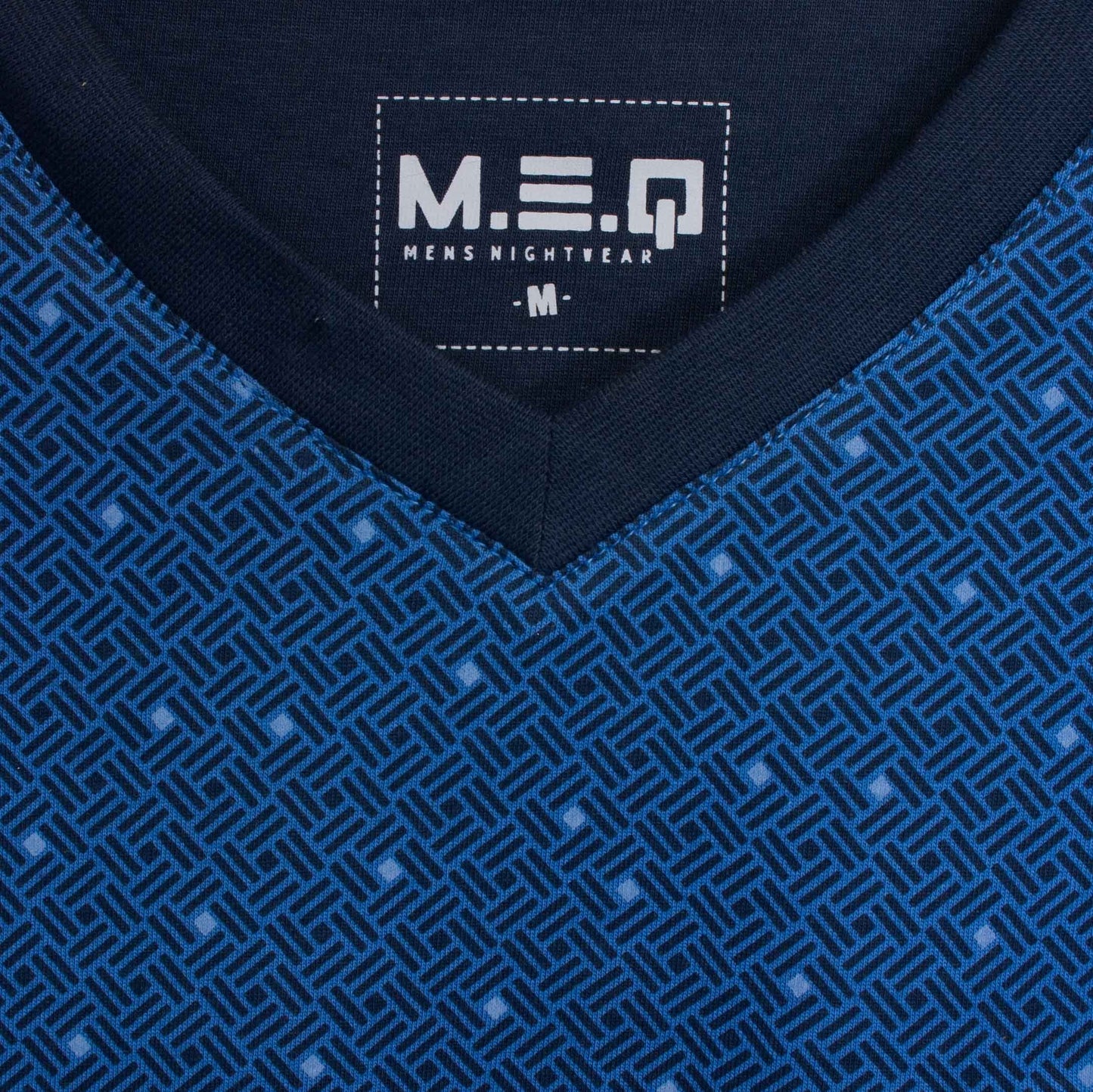 Blauwe pyjama met geometrisch patroon. MEQ logo zichtbaar op donkerblauw label. V-hals en jersey stof.