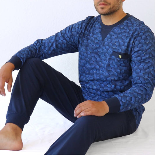 Heren pyjama in blauw met hexagon patroon, lange mouwen en V-hals. Donkerblauwe broek, zittende pose.