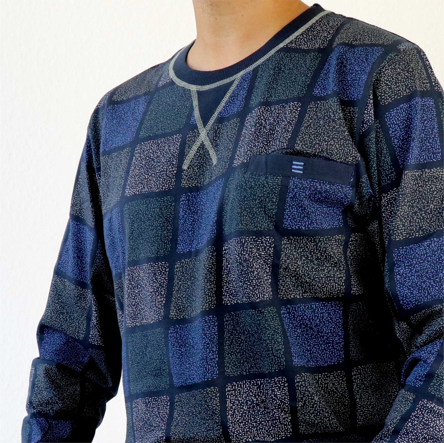 Close-up van een blauwe geruite pyjama met ronde hals, getoond op een model van de borst naar beneden.
