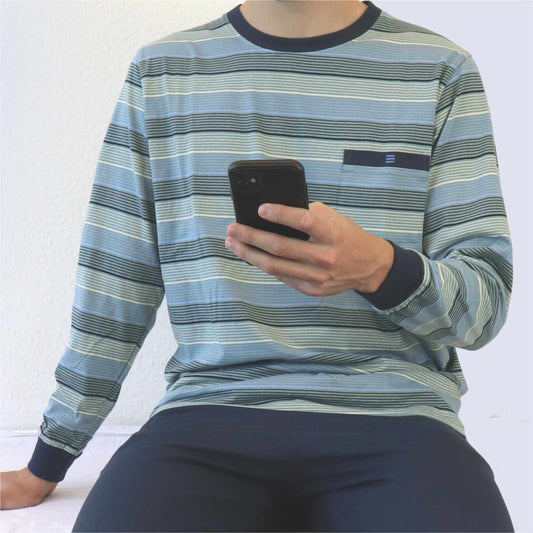 Gestreepte pyjama in groen en blauw tinten met ronde hals en borstzakje. Persoon houdt smartphone vast.