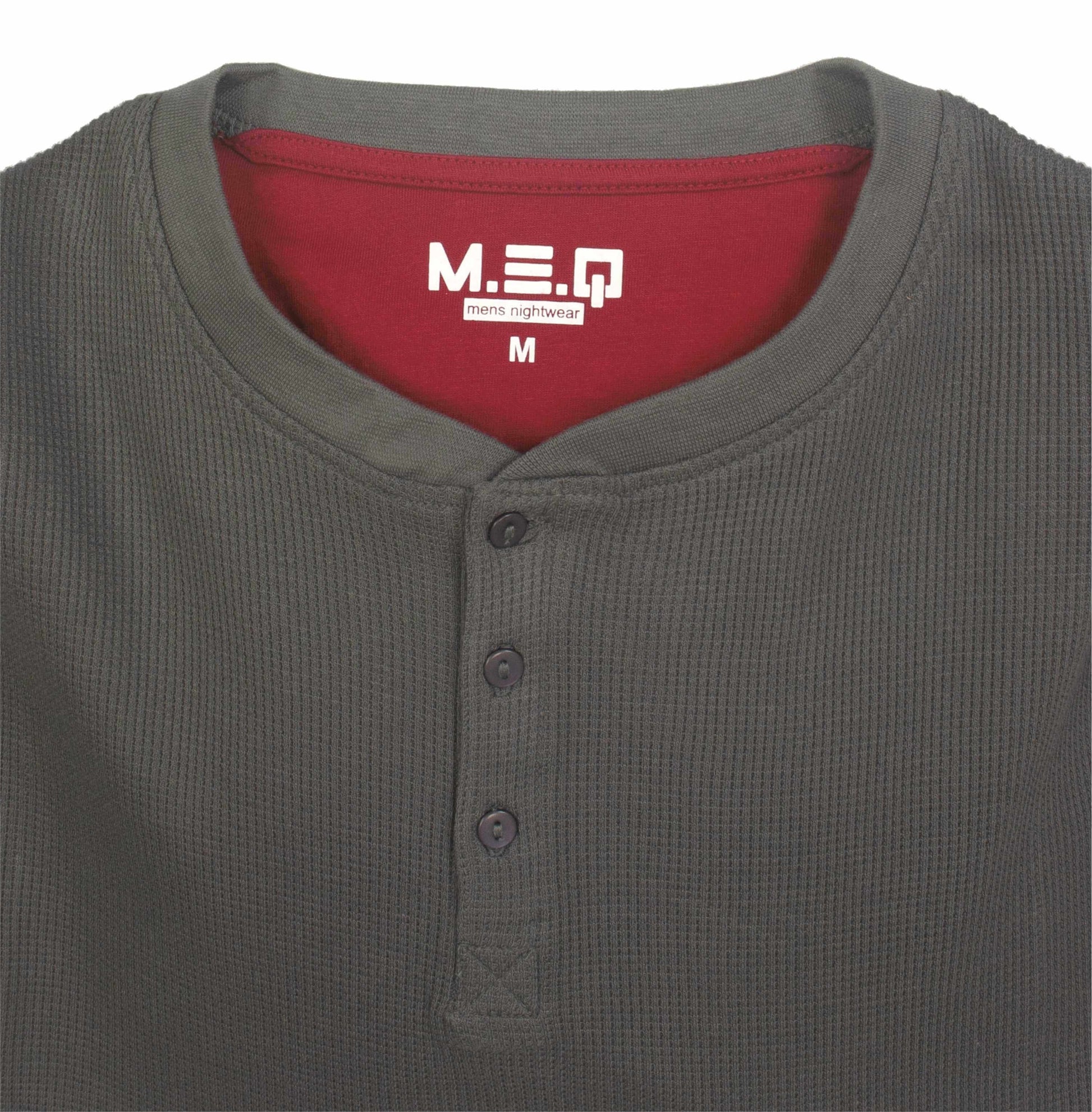 Grijze pyjama top met rode binnenkant, wafelpatroon, polosluiting en MEQ logo op het label, maat M.