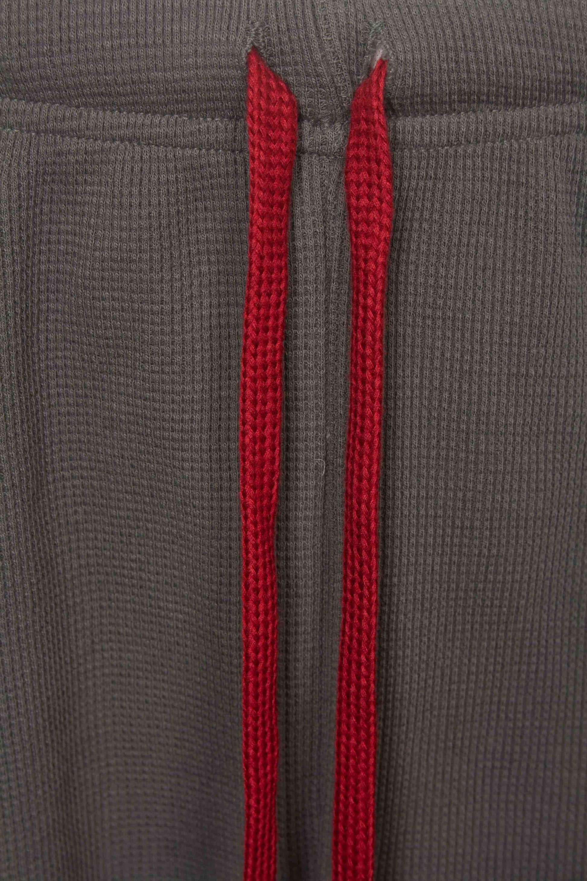 Close-up van grijze stof met twee rode verticale strepen, waarschijnlijk een detail van een pyjama