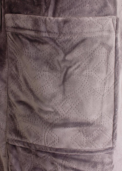 Close-up van een beige fleece badjas met gestanst dessin en opgestikte zak, gemaakt van zacht velours materiaal.