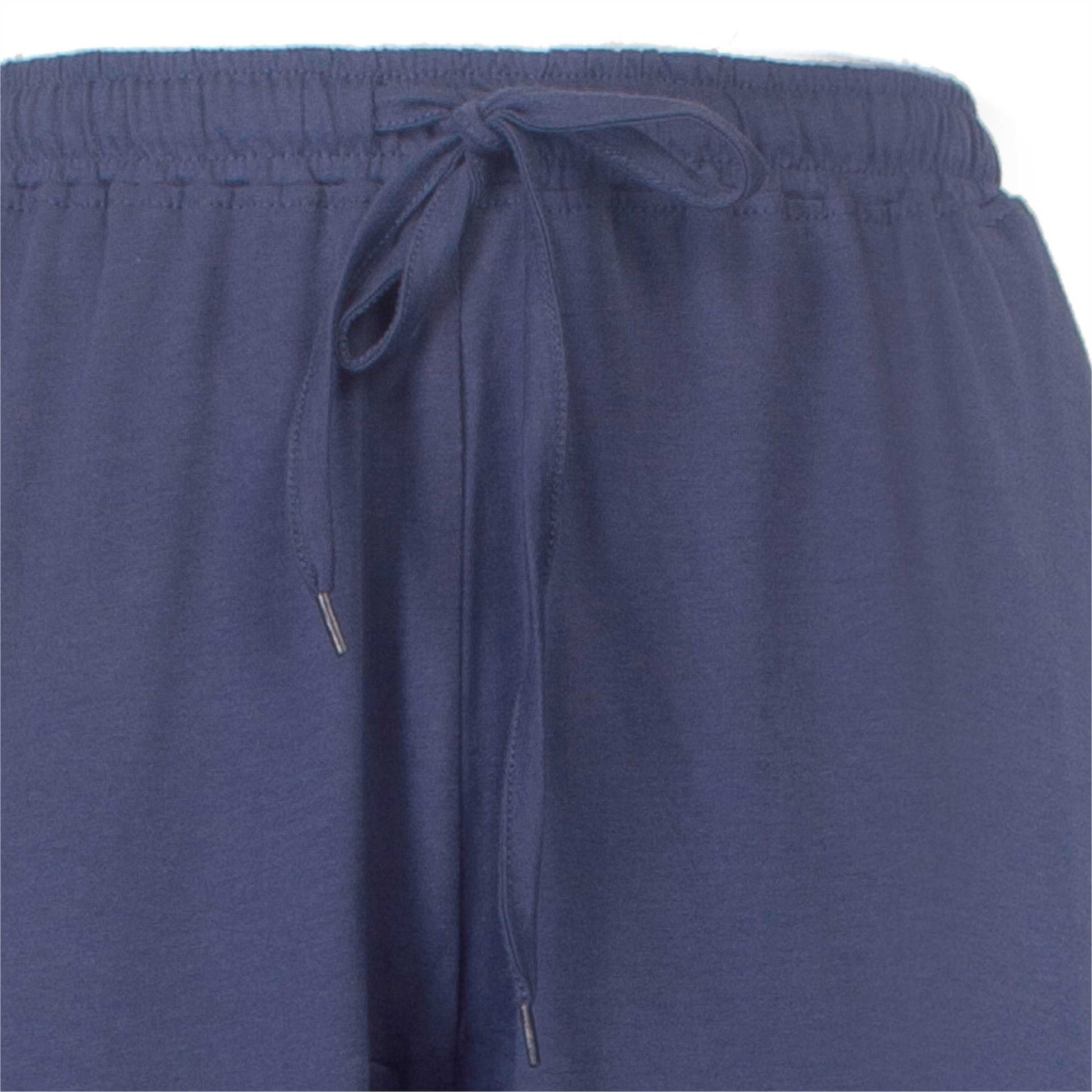 Close-up van een blauwe pyjama broek met een elastische tailleband en een aantrekkoord met metalen uiteinden.