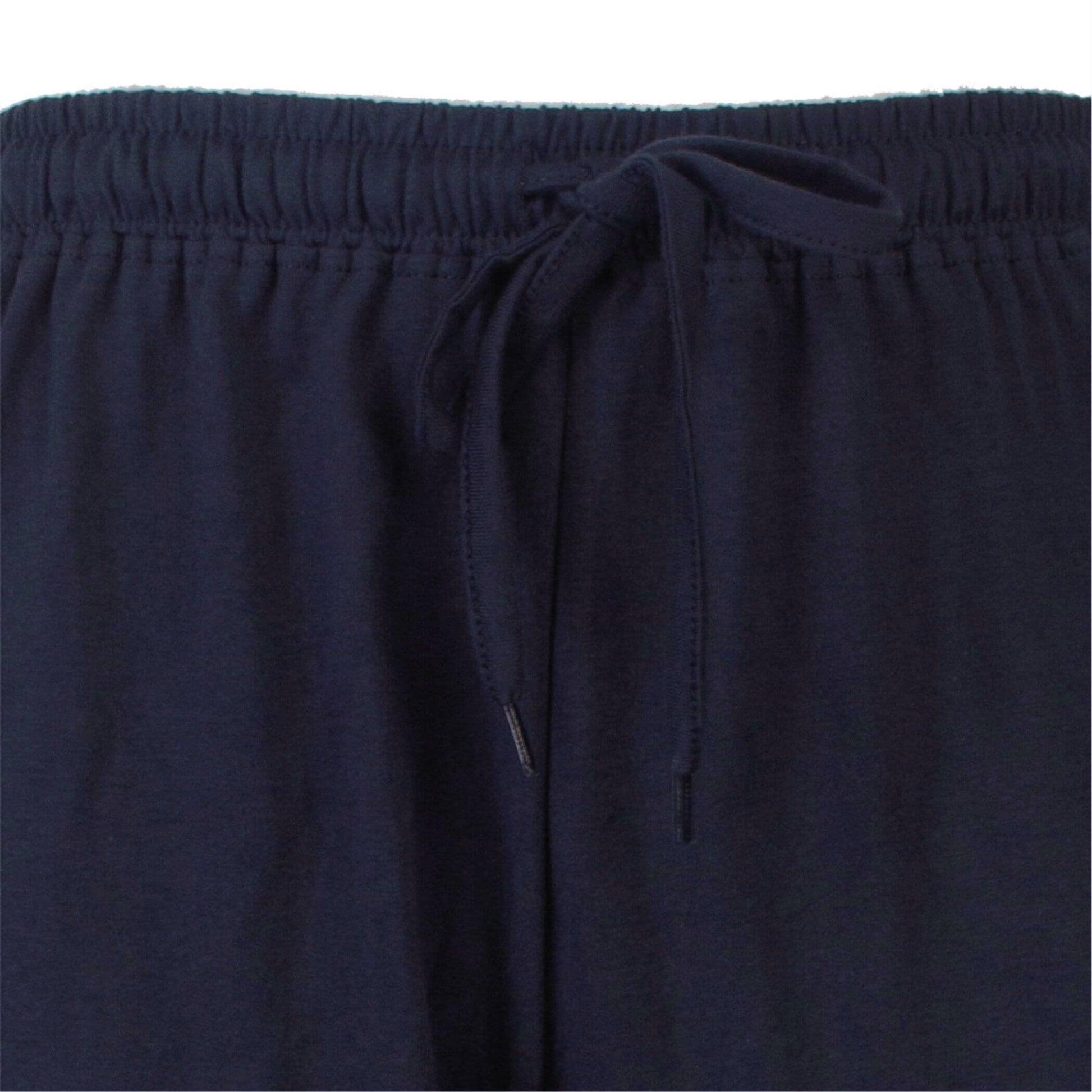 Close-up van een donkerblauwe pyjama broek met elastische tailleband en aantrekkoord aan de voorkant.