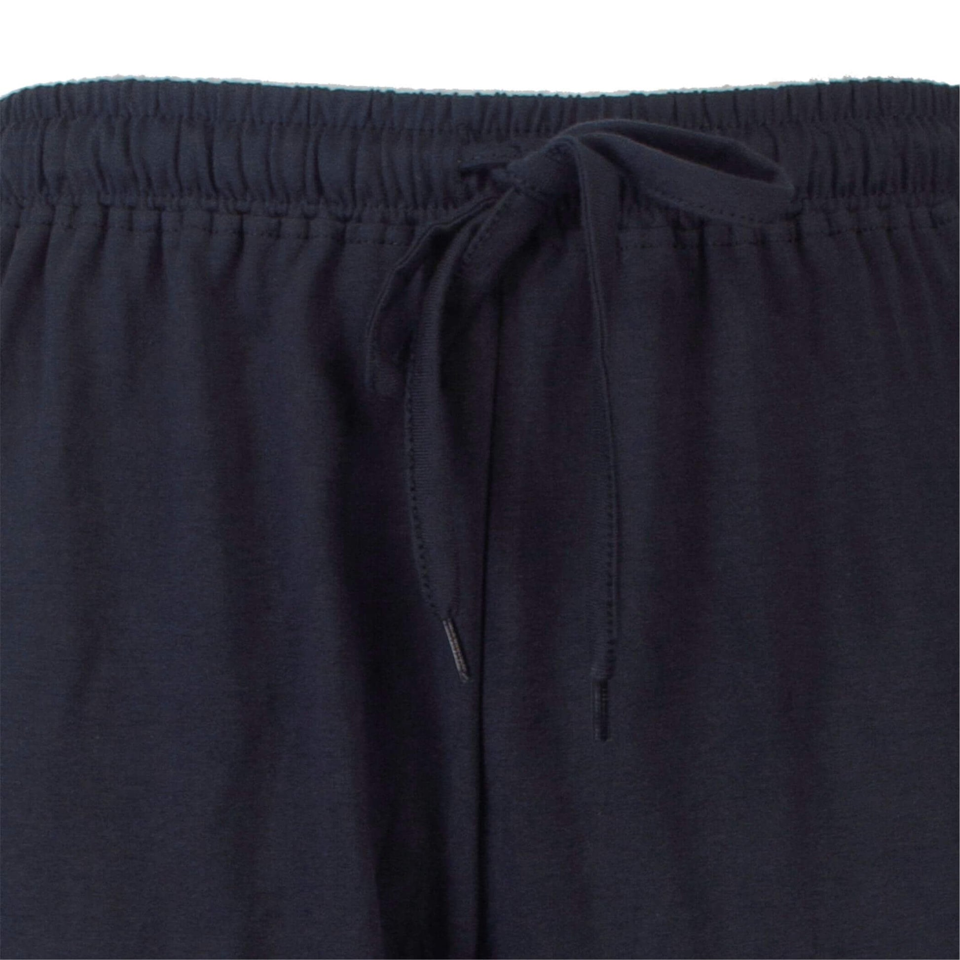 Close-up van de taille van een donkerblauwe pyjamabroek met elastische band en aantrekkoord.
