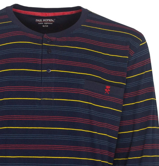 Donkerblauwe pyjama top met horizontale strepen in rood, geel en blauw. Ronde hals met knoopsluiting en borstzakje.